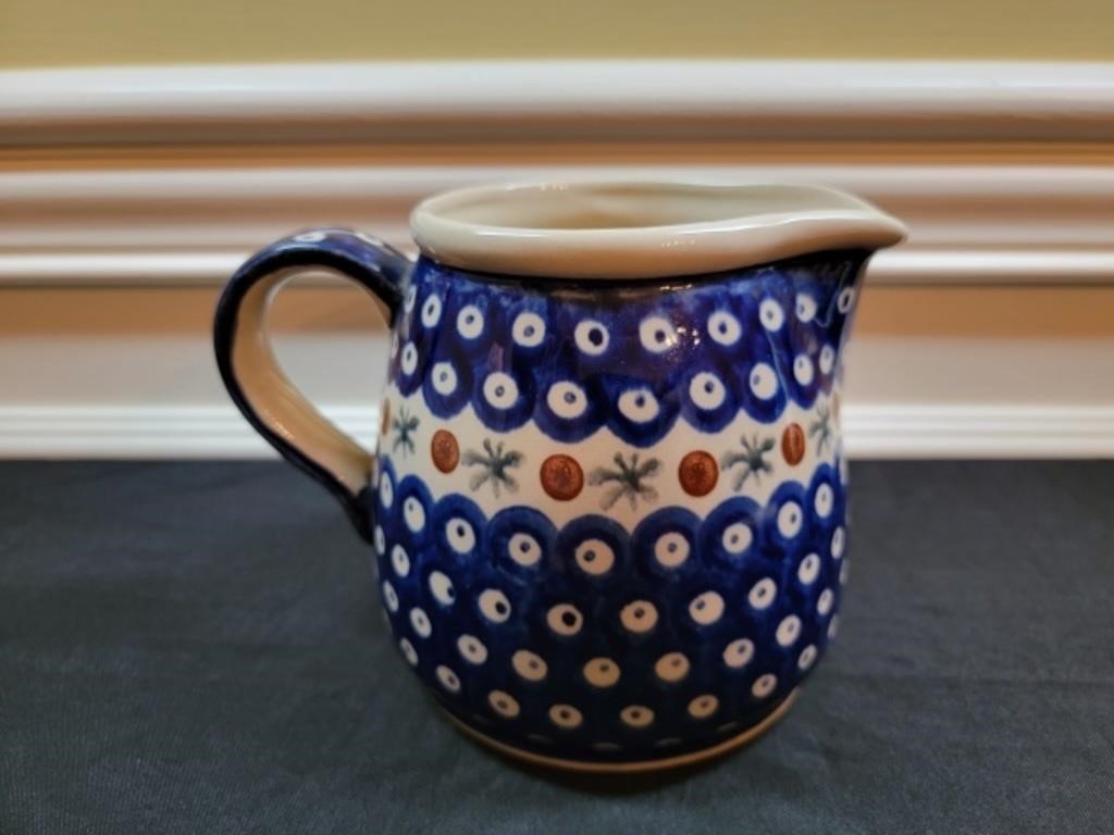 A white ceramic pitcher with blue circle designs across the top and bottom.