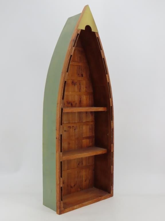 A green bookshelf in the shape of a canoe.